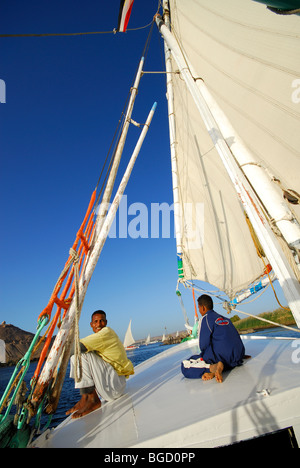 ASWAN, ÄGYPTEN. Ein junger nubischen Mann und junge sitzt auf dem Bug einer Feluke auf dem Nil. Stockfoto