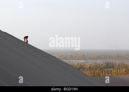 Junge Chinesin fotografieren Mondsichelsee mit die chinesische Pagode von den Sanddünen der Wüste Gobi, in Dunhuang Stockfoto