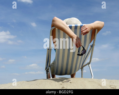 Frau im Liegestuhl am Strand Sonnenbaden Schuss gegen blauen Himmel Stockfoto