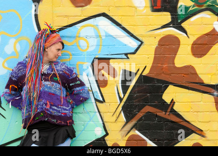 Junge weibliche Hippie mit Multi coloriertes Haar gegen Graffitiwand voll Modell veröffentlicht Stockfoto