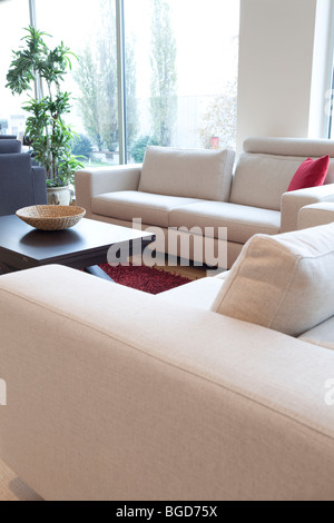 Wohnzimmer mit weißen Sofas durch die Fenster und ethnische Couchtisch Stockfoto