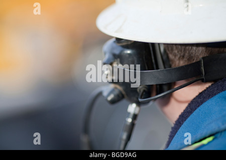 Einen Blick auf ein Industriearbeiter von hinten beim tragen Kopfhörer und einen Schutzhelm Stockfoto