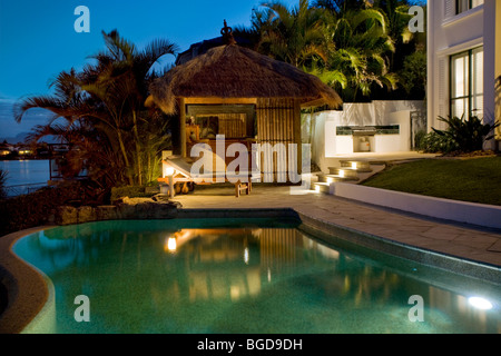 Luxuriöses Herrenhaus Fassade bei Sonnenuntergang mit Blick auf Pool und Bali-Hütte Stockfoto