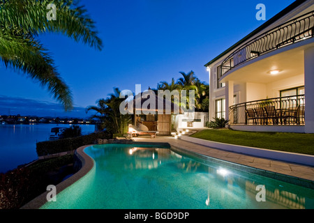 Luxuriöses Herrenhaus Fassade bei Sonnenuntergang mit Blick auf Pool und Kanal Bali Hütte Stockfoto