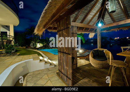 Luxuriöses Herrenhaus Fassade bei Sonnenuntergang mit Blick auf Pool und Kanal Bali Hütte Stockfoto