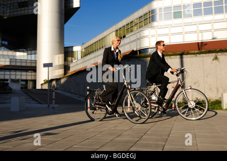 Business-Leute Reiten auf Elektro-Fahrräder, Pedelecs, Hypo-Hochhaus bauen, München, Bayern, Deutschland, Europa Stockfoto