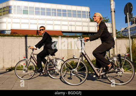 Business-Leute Reiten auf Elektro-Fahrräder, Pedelecs, Hypo-Hochhaus bauen, München, Bayern, Deutschland, Europa Stockfoto