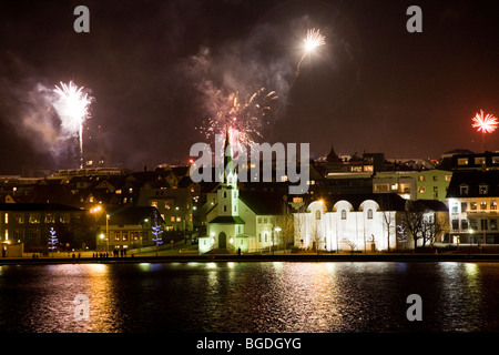 Silvester-Feuerwerk um Mitternacht. Die Innenstadt von Reykjavik, Island. Frikirkjan Kirche (C) und The National Gallery of Iceland (R). Stockfoto