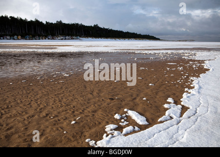 Schnee am Strand bricht mit der Flut Stockfoto