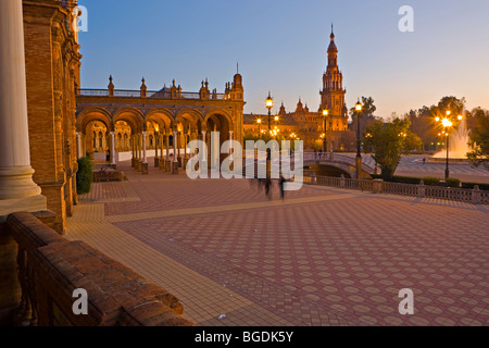 Turm, Brücke und Brunnen aus dem zentralen Gebäude an der Plaza de España, Parque Maria Luisa, während der Dämmerung in der Stadt gesehen Stockfoto