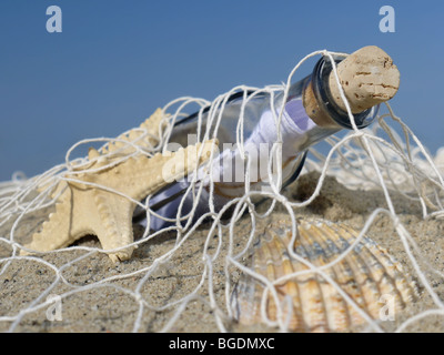 Seestern, Muschel und Flasche mit der Nachricht in das Fischernetz gefangen Stockfoto