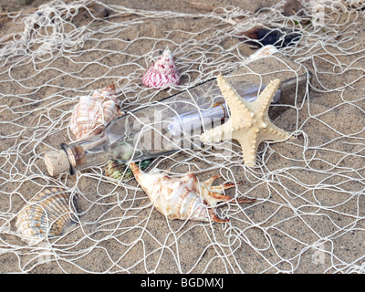 Seesterne, Muscheln und Flasche mit der Nachricht in das Fischernetz gefangen Stockfoto