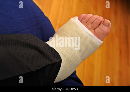 Detail eines Mannes ist Fuß in einem Gipsverband, ruht auf einem Kissen kaputt. Stockfoto