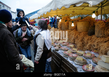 Stock Foto eines Kindes auf eine Erwachsene Schultern ein Stück Käse gegeben durch einen französischen Markt Standinhaber versuchen. Stockfoto