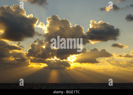 Dramatischer Sonnenaufgang (oder Sonnenuntergang, falls erforderlich) Mit Sonnenstrahlen oder Sonnenstrahl des Sonnenlichts, der durch die Dunkelheit platzt Wolken und klarer blauer Himmel über und darüber hinaus Stockfoto