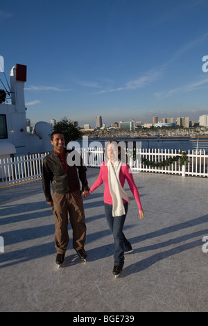 Paar-Eislaufen auf eine synthetische Eisbahn an Bord der Queen Mary Hotel und Attraktion in Long Beach, Kalifornien Stockfoto