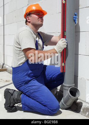 Klempner-Tonwert für die Überprüfung der Lotlinie des montierten pvc-Abwasserrohre innen unfertige Haus Stockfoto