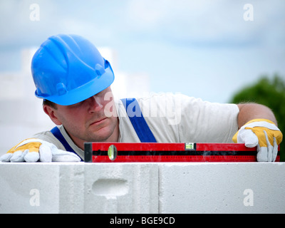 Mason, die Überprüfung der horizontalen Ebene der Hauswand Schicht aus Porenbeton autoklaviert Betonsteine Stockfoto