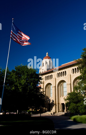 Der Hoover Tower steht hinter einer amerikanischen Flagge an der Stanford University, an einem klaren Tag mit blauem Himmel, Stanford, Kalifornien, USA. Stockfoto