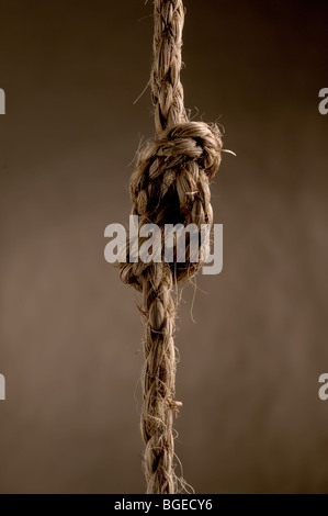 Seil in einem Bogen Knoten gegen einen strukturierten braunen Hintergrund Stockfoto