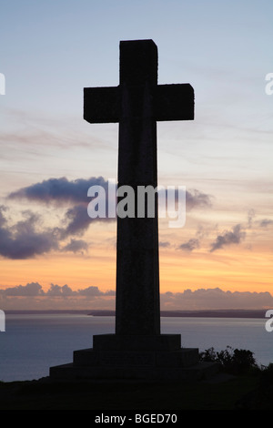 Christliches Kreuz Silhoutted gegen einen Sonnenuntergang über Meer Stockfoto