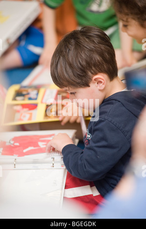 Drei Jahre Alter spanischer Junge sammelt seine Sachen an seinem letzten Tag der Vorschule einschließlich Projektordner Stockfoto