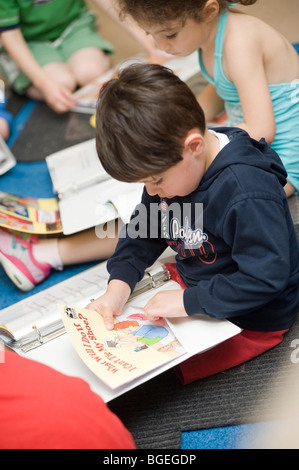 Drei Jahre Alter spanischer Junge sammelt seine Sachen an seinem letzten Tag der Vorschule einschließlich Projektordner Stockfoto