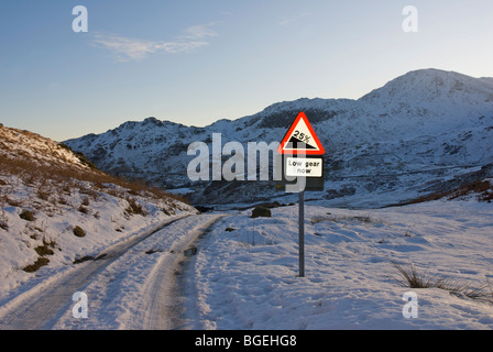 Verschneite Straße und Schild Warnung vor steilen Hügel, kleine Langdale, Nationalpark Lake District, Cumbria, England UK Stockfoto