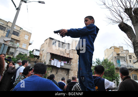 Junge arabische jungen weist eine Handfeuerwaffe in die Menge Stockfoto