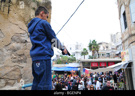 Junge arabische jungen weist eine Handfeuerwaffe in die Menge Stockfoto