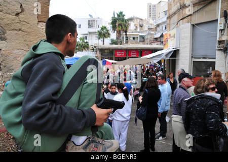 Junge arabische jungen weist eine Handfeuerwaffe in die Menge Stockfoto