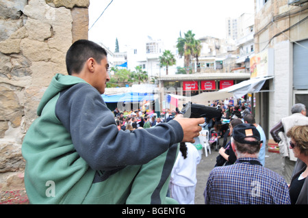 Junge arabische jungen weist eine Handfeuerwaffe in die Menge Stockfoto