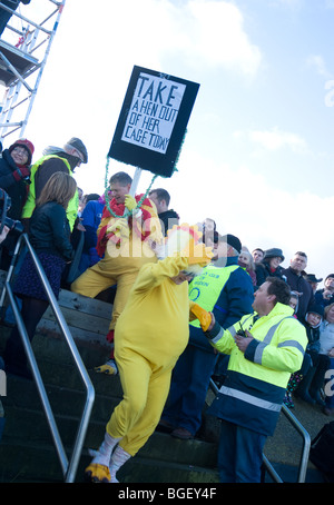 Konkurrenten als Huhn verkleidet und tragen ein Plakat Weg die Anfangszeile des die das Maldon-Schlamm-Rennen Stockfoto