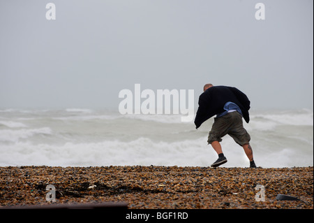 Seaford in Sussex-stürmisches Wetter zieht die Menschen an den Strand. Dieser Mann sieht man kämpfen, um zu Fuß in den Sturm Windstärke. Stockfoto