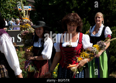 Frauen tragen Dirndl und halten Blumen in Jubel-Stimmung in Deutschland Stockfoto