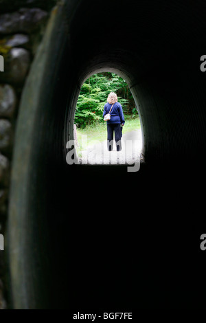 Frau am anderen Ende eines Tunnels in Olympic Nationalpark, Washington. Stockfoto