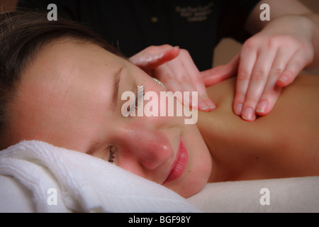 Eine junge Frau genießen Sie eine entspannende Massage für Rücken und Schulter. Stockfoto