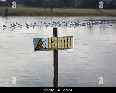 Gefahr, dünnem Eis, Wegweiser auf zugefrorenen Teich, Wimbledon Common, London Stockfoto