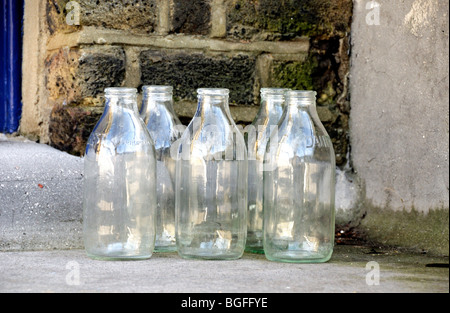 Fünf leere Milchflaschen vor Haustür Stockfoto