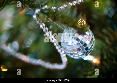 Eine Mini-Disco-Kugel hängt an einem Weihnachtsbaum mit Silberperlen. Stockfoto