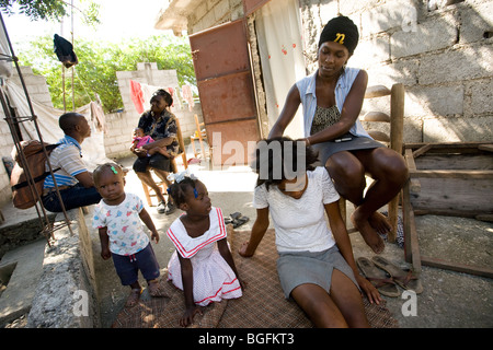 Eine Familie Litzen gegenseitig die Haare vor ihrem Haus in Croix-des-Bouquet, Haiti. Stockfoto