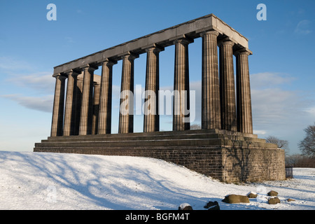 Das National Monument auf Edinburghs Calton Hill an einem klaren Wintertag. Schnee liegt auf dem Boden im Vordergrund. Stockfoto