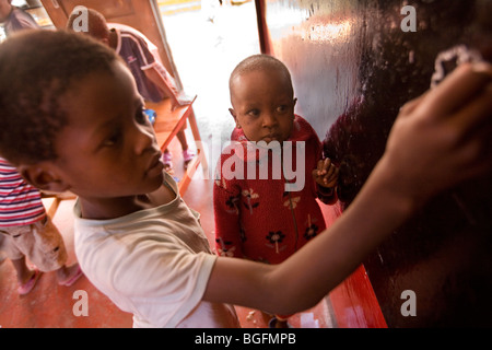 Ein kleiner Junge stützt sich auf eine Tafel in einem Waisenhaus in Kilimanjaro-Region, Tanzani, Ost-Afrika. Stockfoto