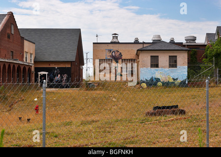 Gebäude mit Wandmalereien hinter einem Maschendrahtzaun im ehemaligen Lorton Correctional Complex, Lorton, Virginia. Stockfoto