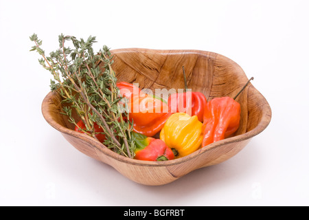 Gemischte Caribbean scotch Bonnet Chili mit Haufen von Thymian Zweige in Holzschale vor weißem Hintergrund Stockfoto