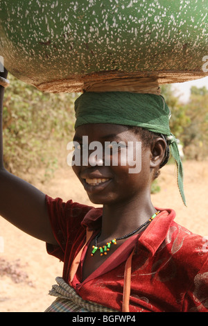 Eine junge Frau trägt Wasser auf dem Kopf in einem trockenen Flussbett, Burkina Faso, Westafrika Stockfoto