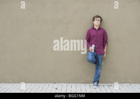 Junge in kariertes Hemd und Jeans Wand gelehnt Stockfoto