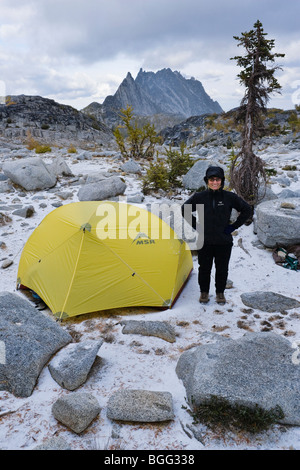 Eine Frau, die ein Lächeln auf den Lippen vor ihrem Zelt in die Verzauberung Lakes Wilderness Area, Kaskaden von Washington, USA. Stockfoto