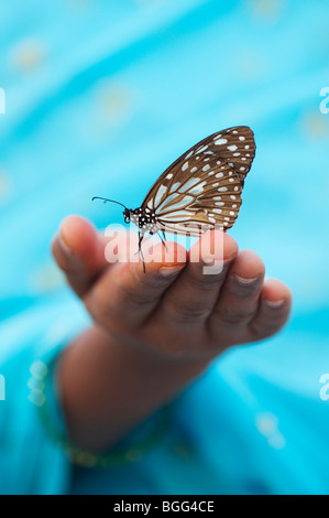 Tirumala limniace. Blue Tiger Schmetterling auf der Hand eines indischen Mädchens. Indien Stockfoto