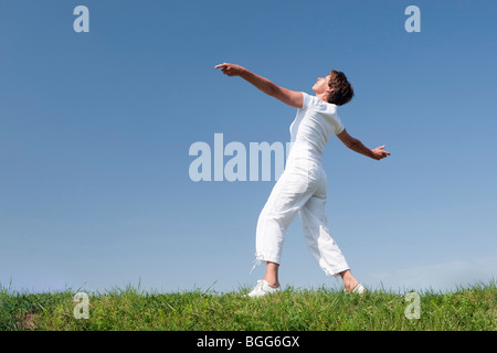 Aktive ältere Frau unternimmt einige Gymnastik vor blauem Himmel Stockfoto